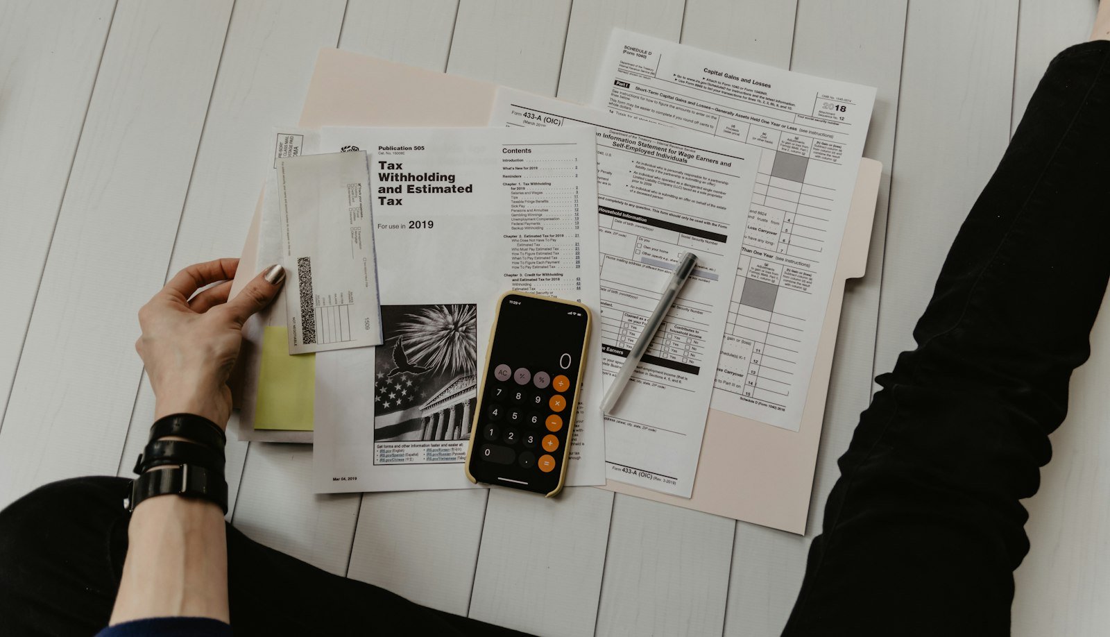 Person holding tax papers near a pen and calculator